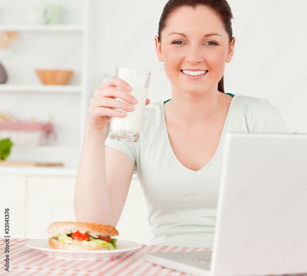 Attractive woman relaxing on her laptop and posing while drinkin Attractive woman relaxing on her laptop and posing while drinkin