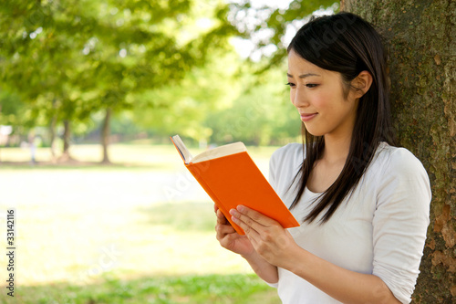 beautiful asian woman reading a book in the park