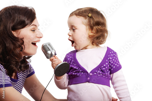 Mother and her little daughter sing into the microphone