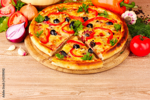 pizza and vegetables on wooden background