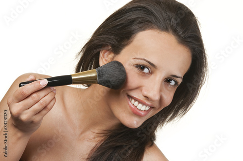 Beautiful young woman applying foundation powder