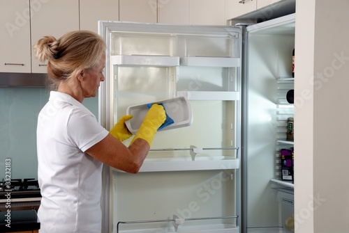 Seniorin putzt Kühlschrank
