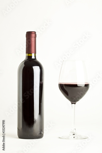 Glass of red wine and a bottle isolated over white background