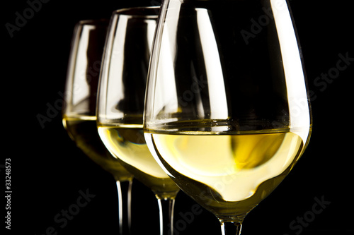 three glasses of white wine on black background