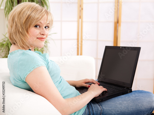 junge Frau sitzt zu hause mit ihrem Laptop auf dem Sofa
