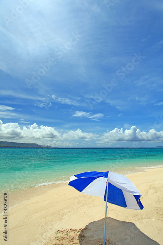 真っ白い砂浜の上に立つビーチパラソル © sunabesyou