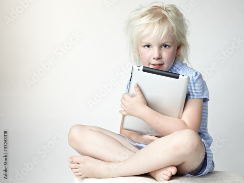 Cute blond girl loves her touchpad so much photo