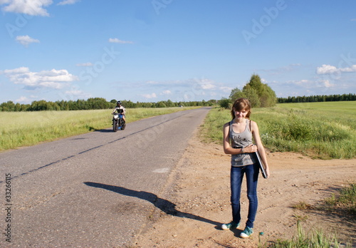Девочка стоит у обочины асфальтированной дороги