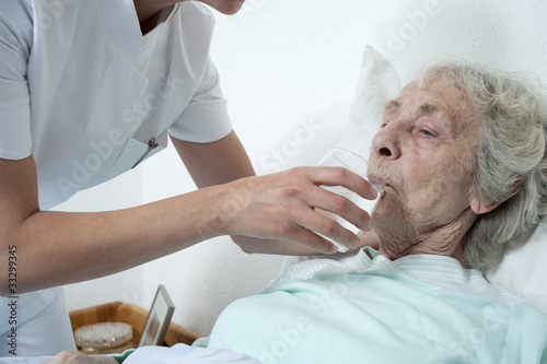 Altenpflegerin reicht wasserglas photo