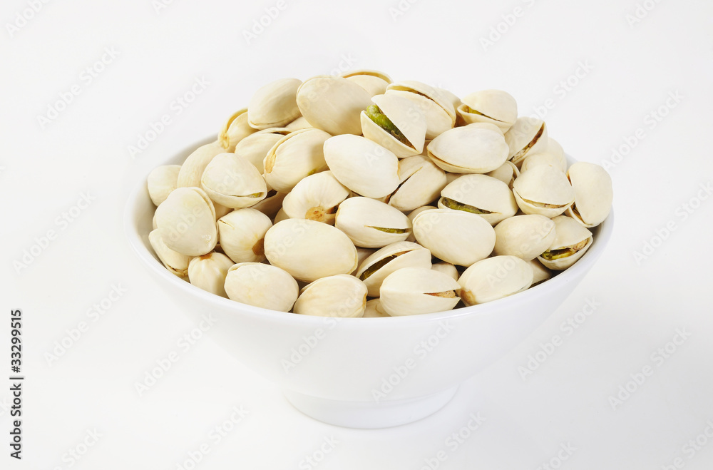 pistachio nuts in a bowl on white background pistachio nuts in a bowl on white background