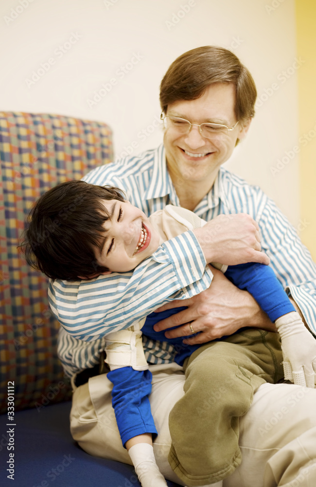 Father holding disabled son in doctor's office Father holding disabled son in doctor's office