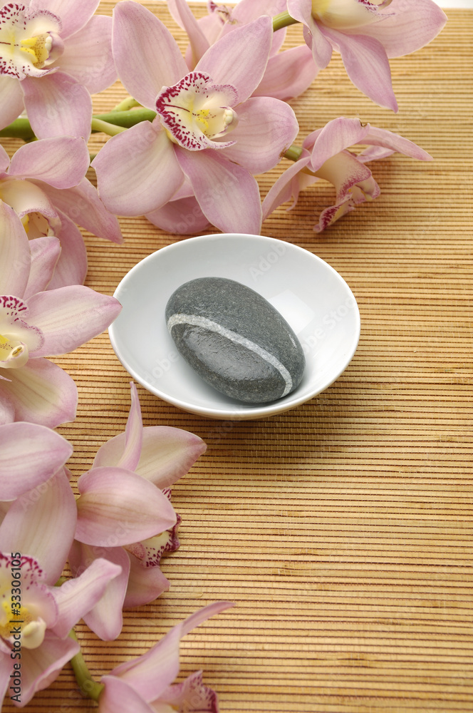 Bowl of zen stones with pink orchid over mat Bowl of zen stones with pink orchid over mat
