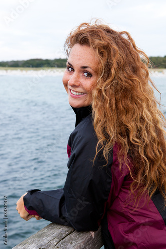 junge Frau in Windjacke auf einer Seebrücke © fotogestoeber