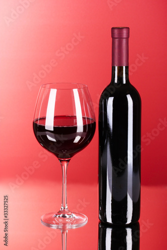 Wine bottle and glass on red background