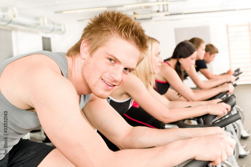 Fitness young man on gym bike spinning Fitness young man on gym bike spinning