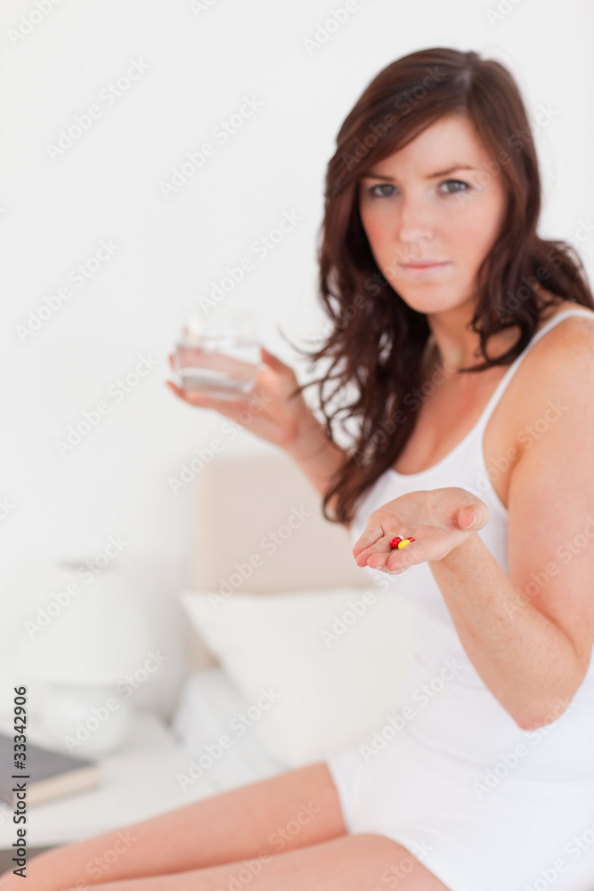 Good looking brunette female taking some pills while sitting Good looking brunette female taking some pills while sitting