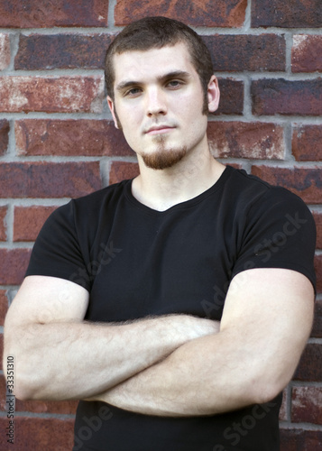 Caucasian Male Leaning against a red brick wall