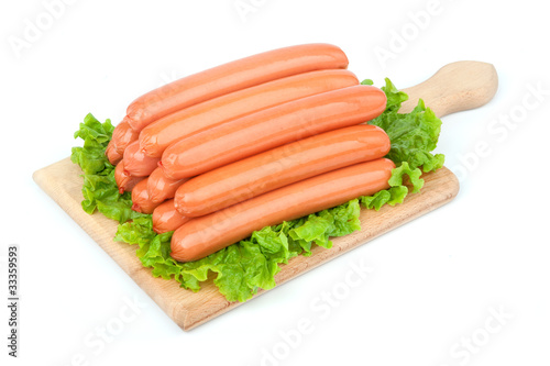 Sausages arranged on cutting board with lettuce