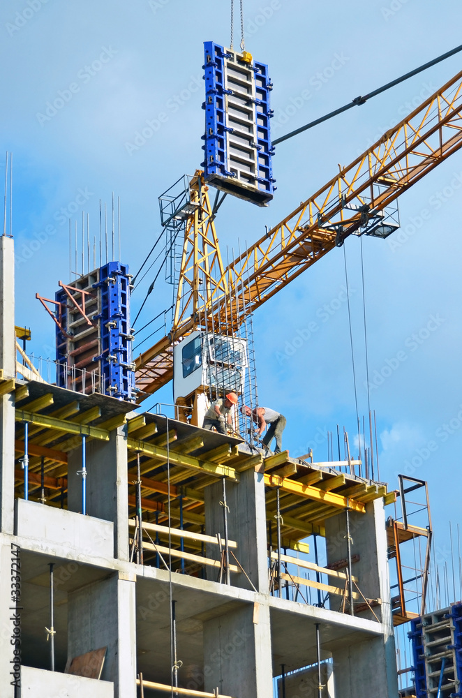 Building crane and building under construction against blue sky Building crane and building under construction against blue sky