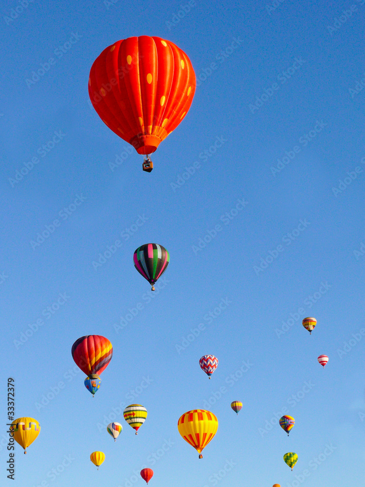 Colorful balloons rising in a blue sky