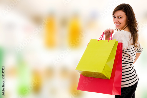 Happy smiling young women with colored bags at the shopping