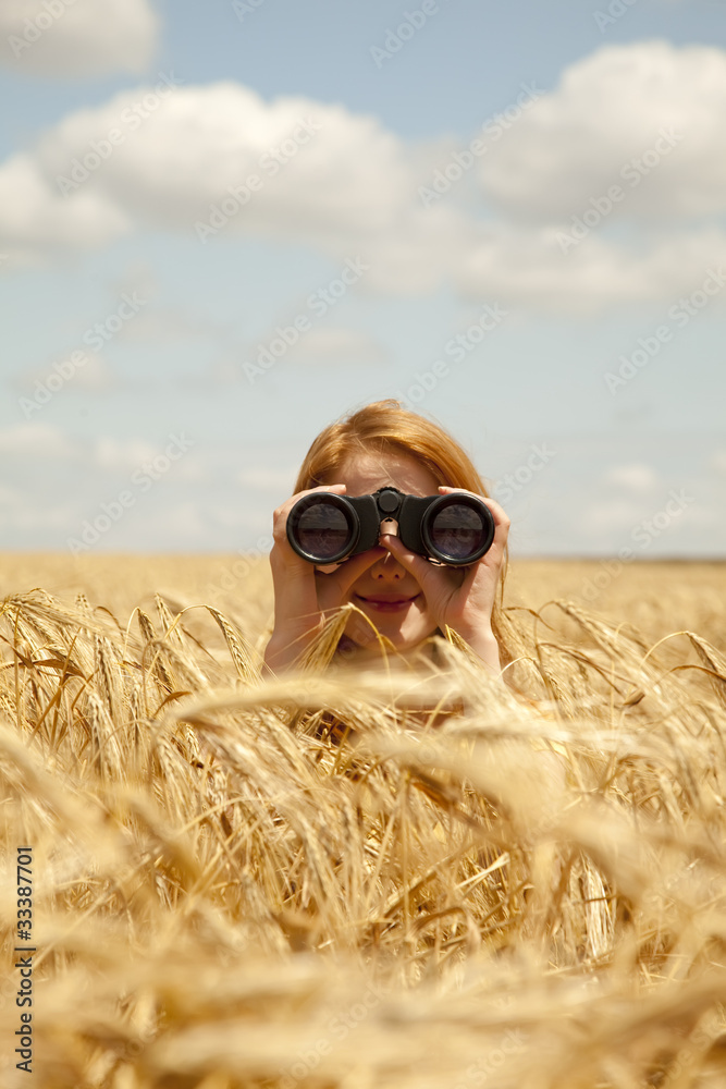 Fototapeta premium Redhead girl with binocular at wheat field.