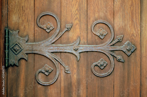 Close-up Of An Ornamental Iron Hinge On An Old Wooden Door