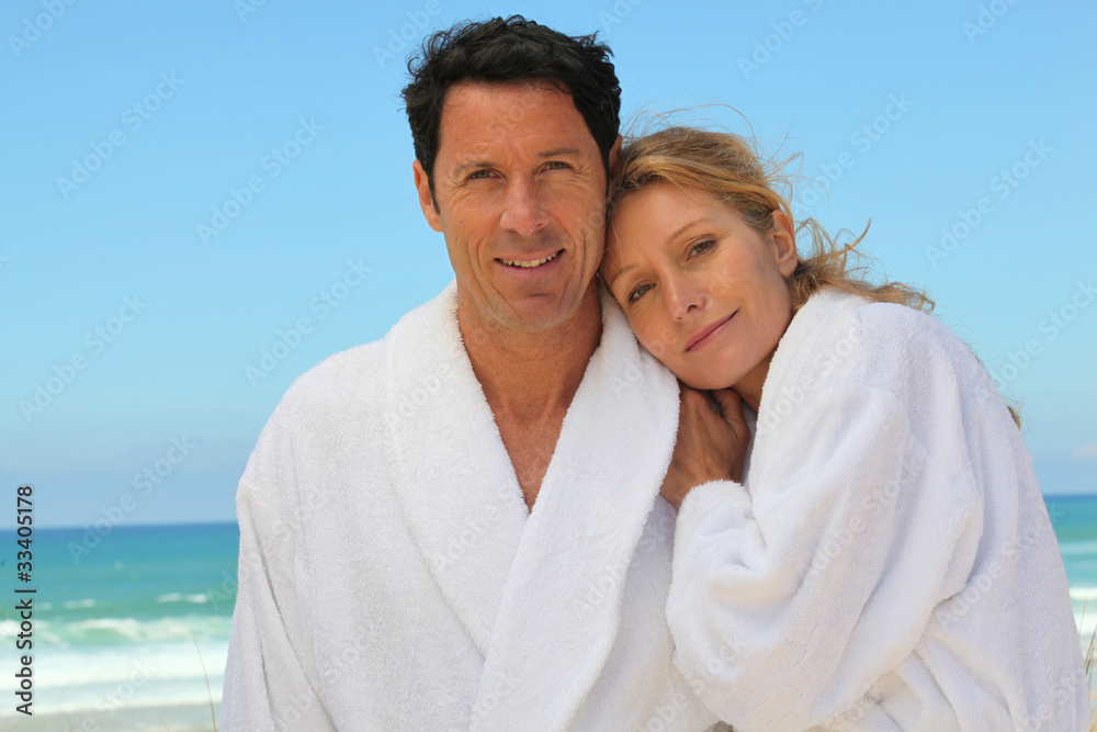 Obraz premium Attractive couple in bathrobes on the beach