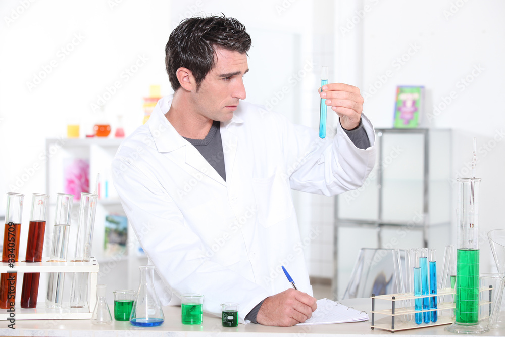 Young man studying the contents of a test tube Young man studying the contents of a test tube