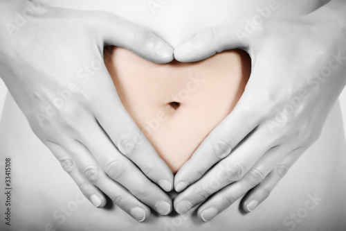 Heart shaped with hands on woman belly