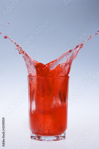 red fruity juice water splash coming out of a glass