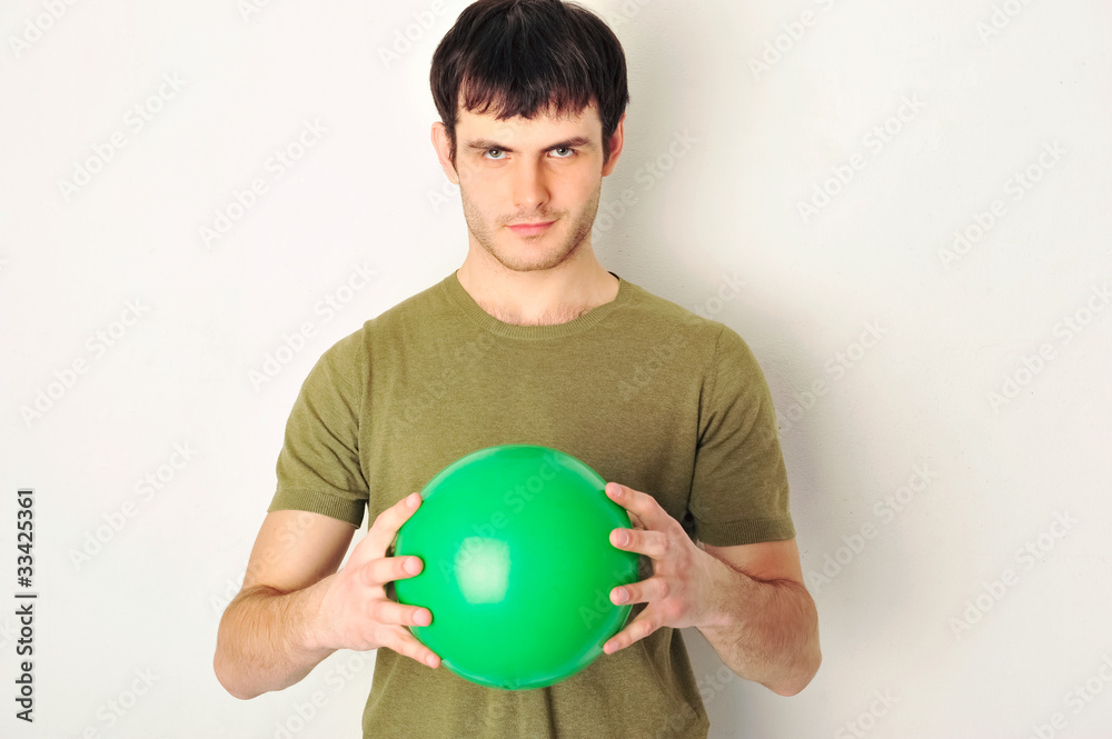 Portrait of handsome man holding green ball in his arms. Standin Portrait of handsome man holding green ball in his arms. Standin