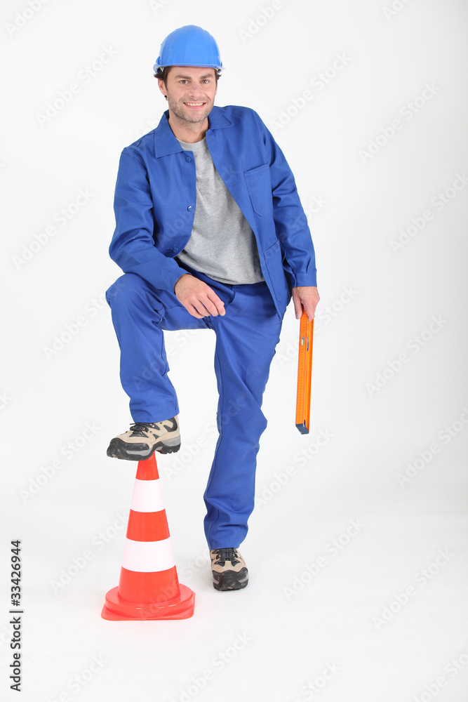 Builder with foot on traffic cone. Builder with foot on traffic cone.