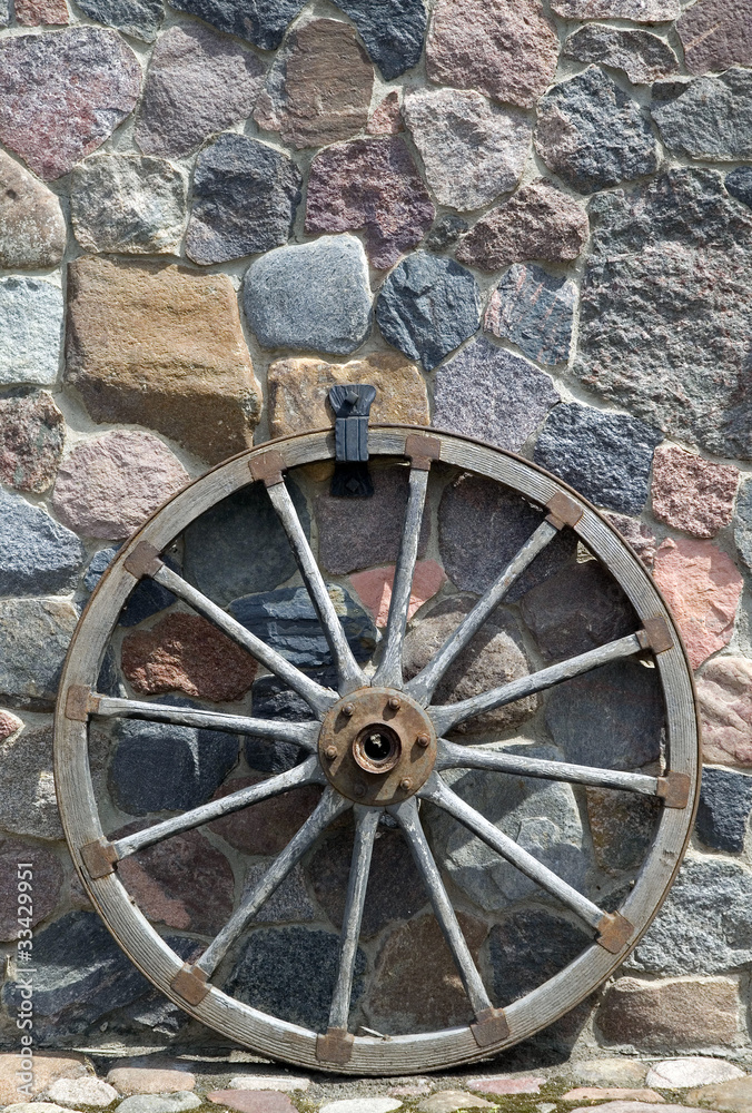 Old wooden wheel is placed near wall