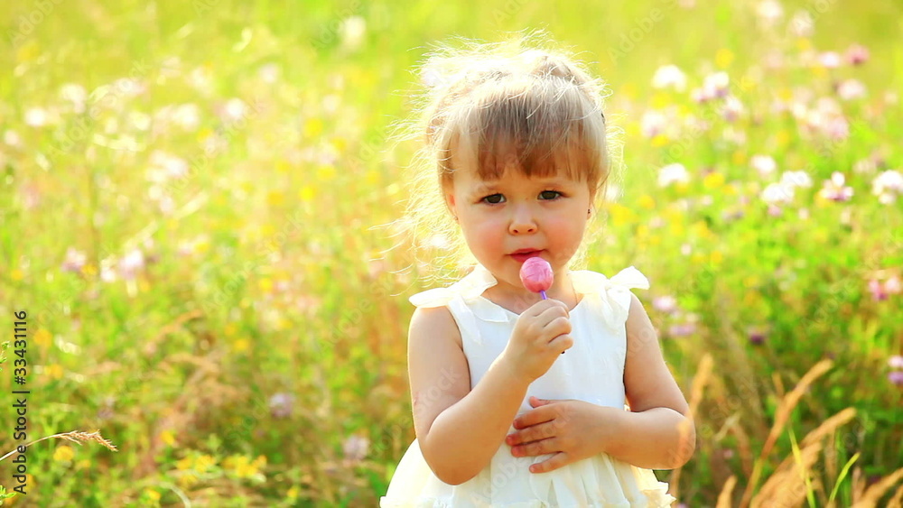 Portrait of child in the field. Chupa Chups girl eating Portrait of child in the field. Chupa Chups girl eating