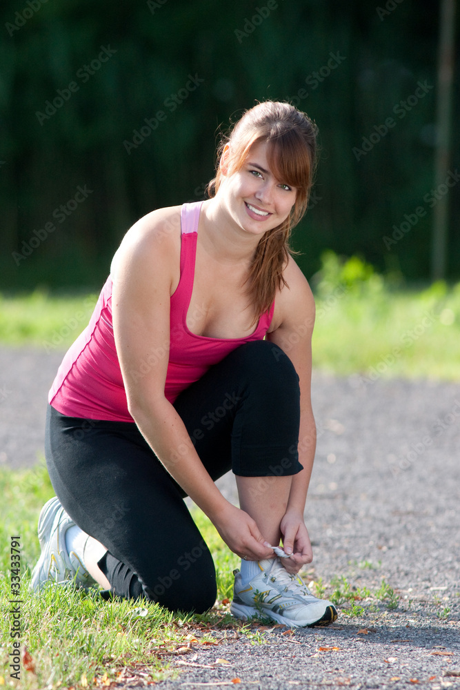 Woman tying her running shoe Woman tying her running shoe