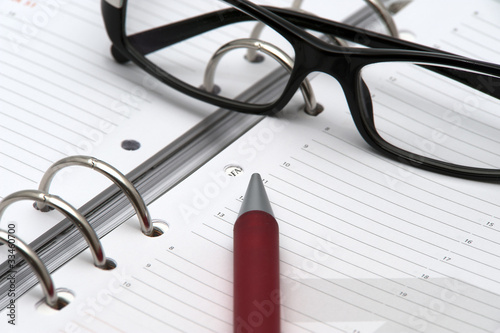 Agenda per appuntamento con occhiali e penna rossa photo