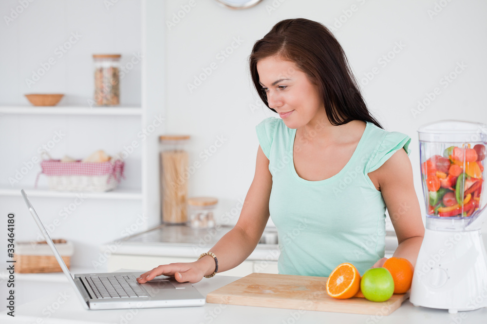 Woman with a laptop and fruits in a blender