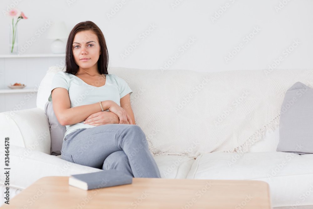 Smiling dark-haired woman sitting on her sofa