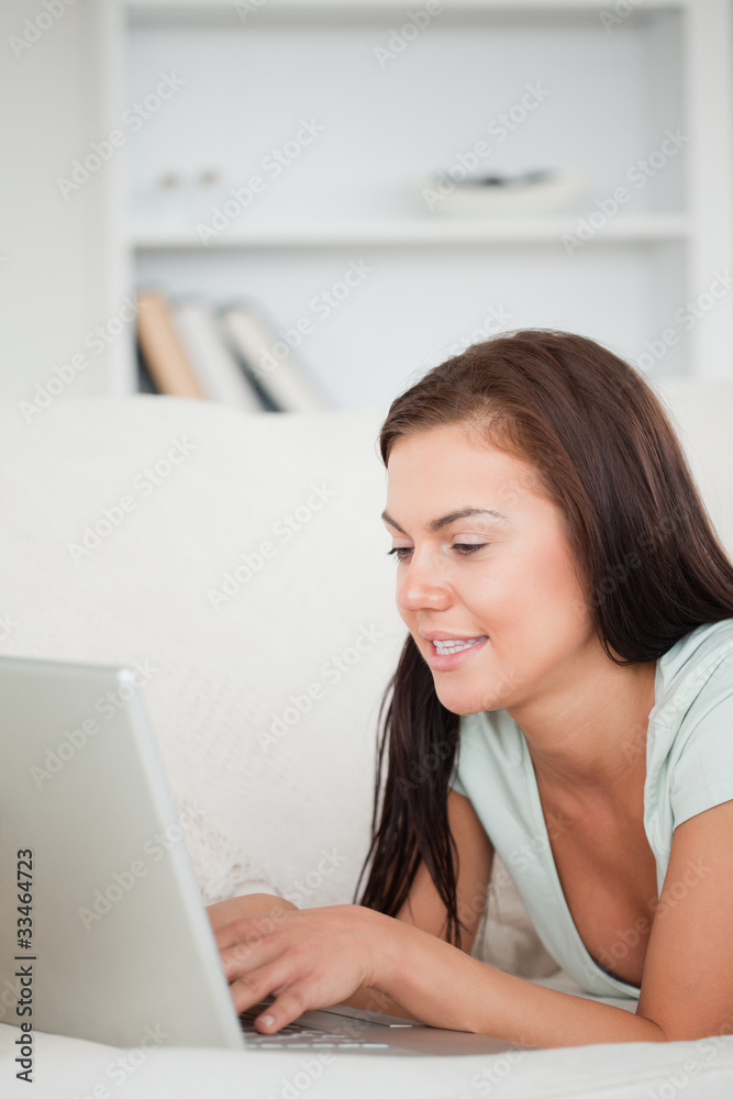 Portrait of a cute brunette on a sofa using a laptop Portrait of a cute brunette on a sofa using a laptop