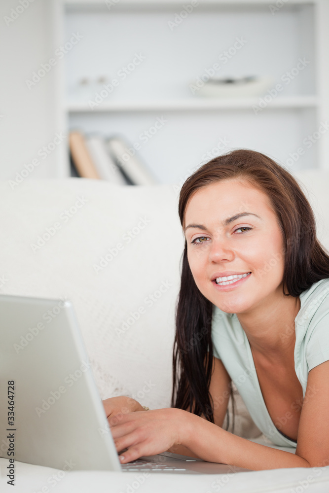 Portrait of a brunette on a sofa using a laptop Portrait of a brunette on a sofa using a laptop