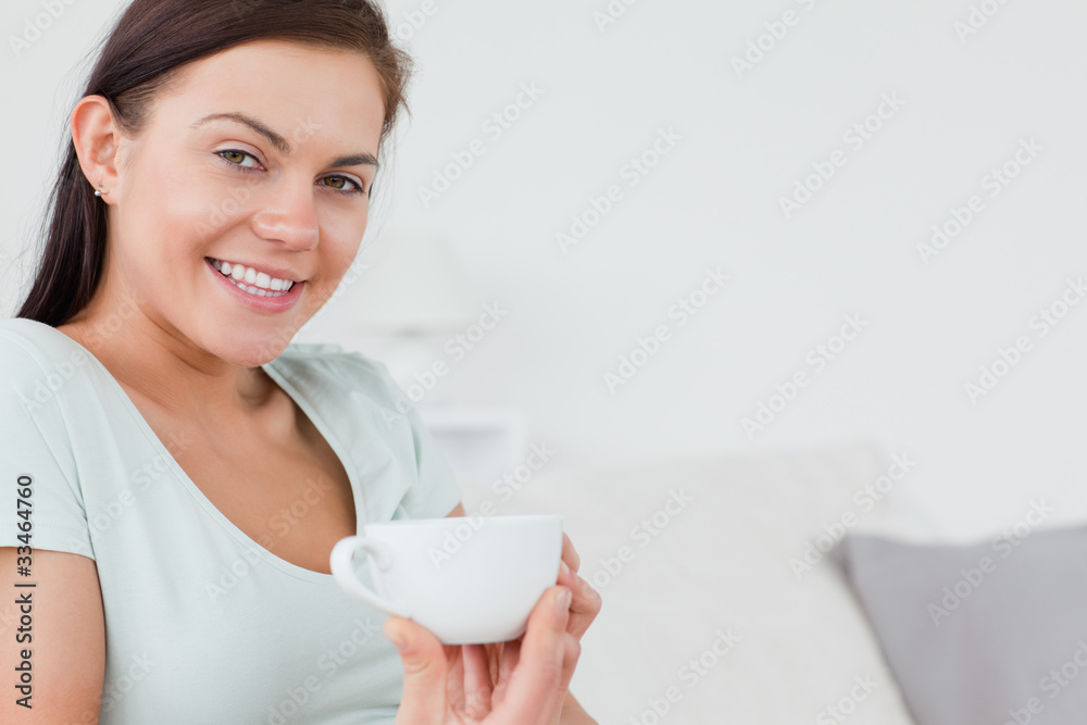 Close up of a brunette sitting on a sofa with a cup of coffee Close up of a brunette sitting on a sofa with a cup of coffee