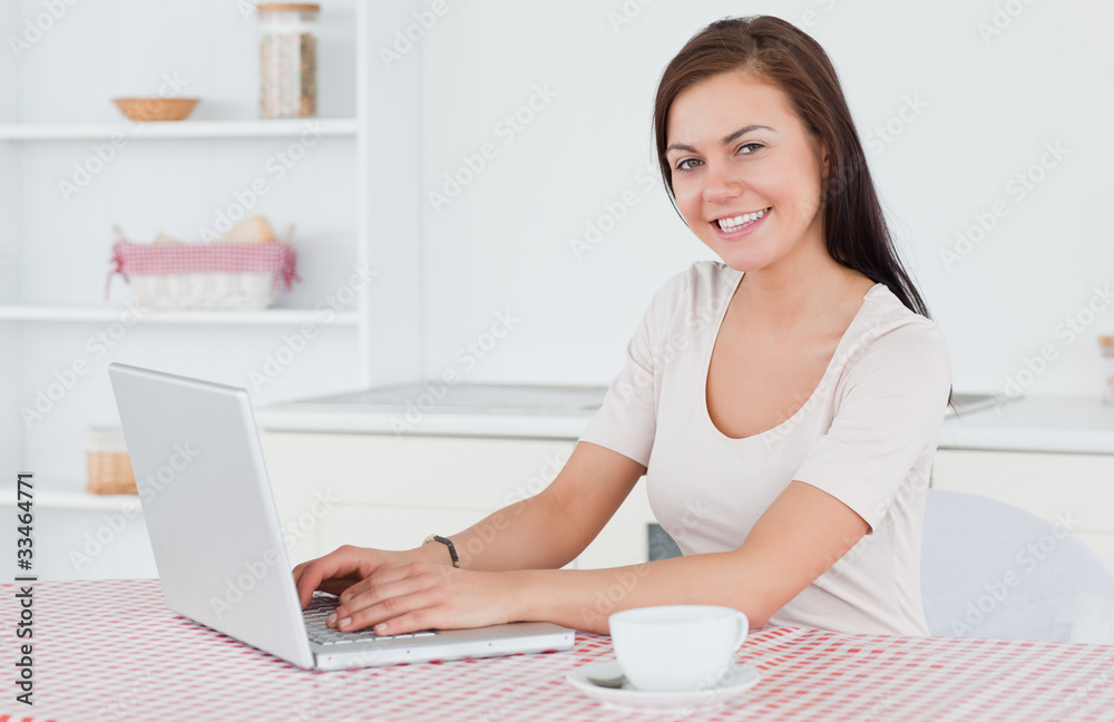 Brunette using her laptop and having a tea Brunette using her laptop and having a tea