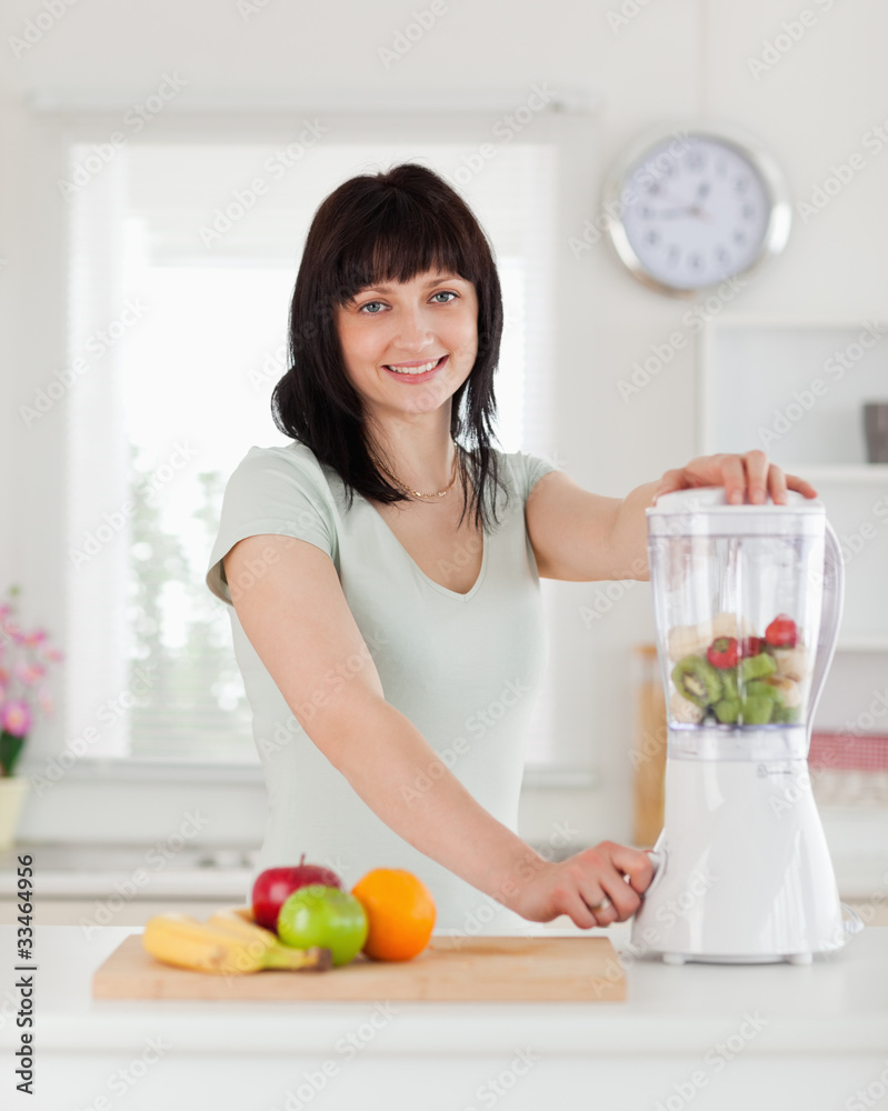 Good looking brunette female using a mixer while standing