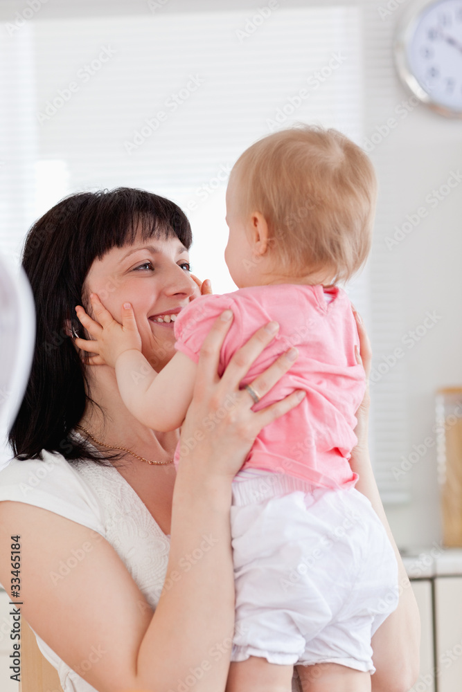 Gorgeous brunette woman holding her baby in her arms while sitti