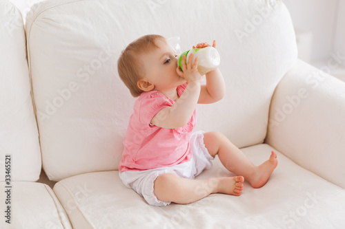 Baby bottle-feeding while sitting on a sofa