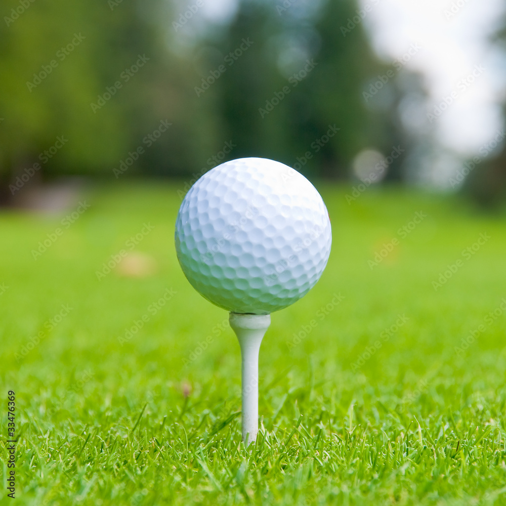 Golf ball on tee over a blurred green. Golf ball on tee over a blurred green.