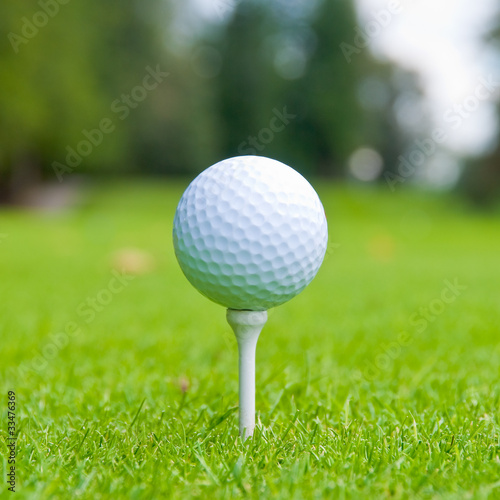 Golf ball on tee over a blurred green.