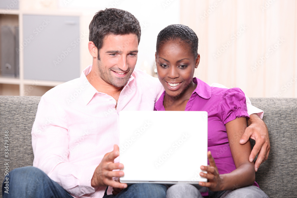 Couple sat on sofa watching laptop screen