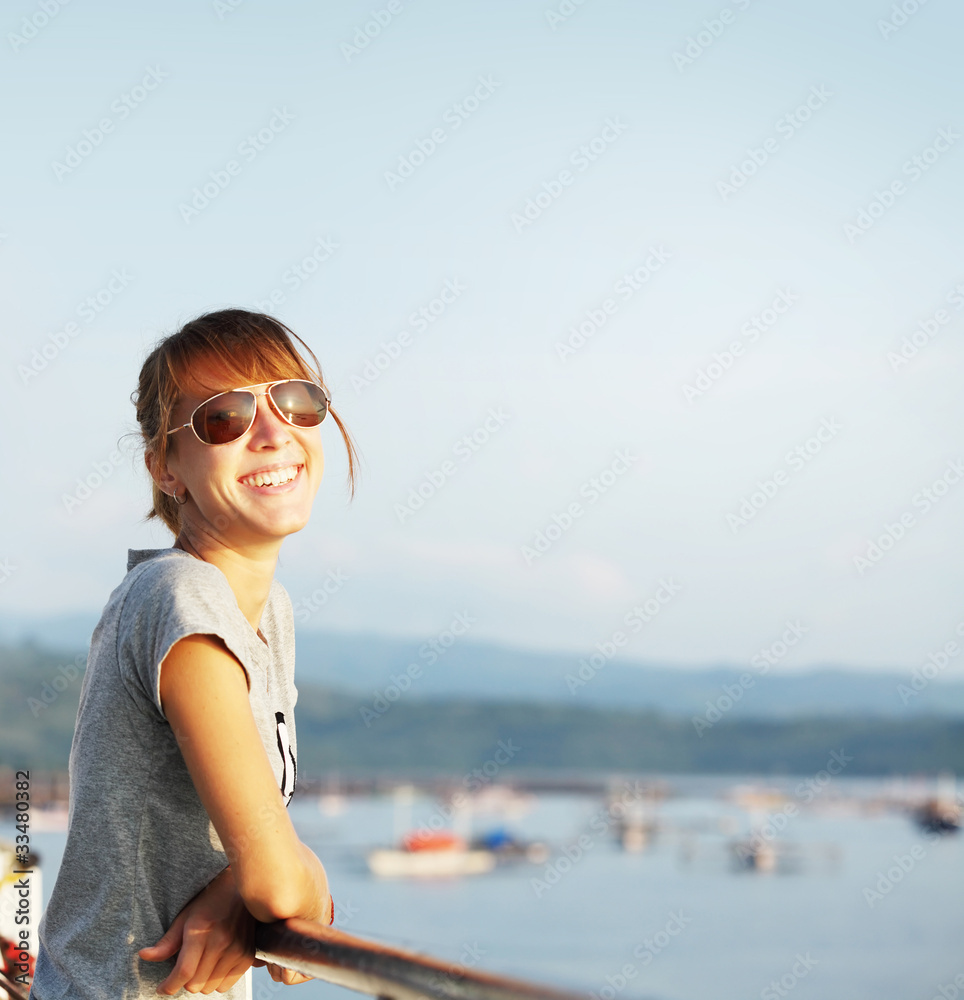 Young smiling woman outdoor portrait on blue airy background with copyspace